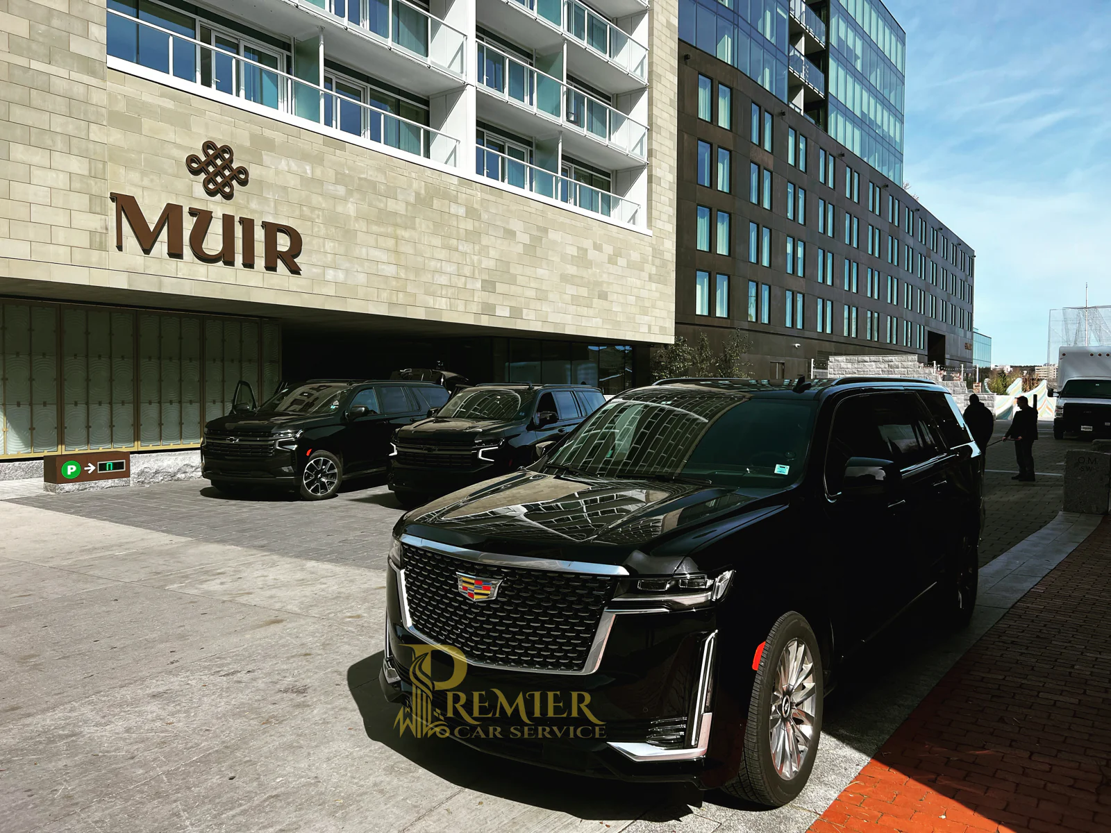 Premier multi-SUV pickup at the Muir Hotel — two Chevrolet Suburbans and a Cadillac Escalade ESV staged at the Queen's Marque entrance