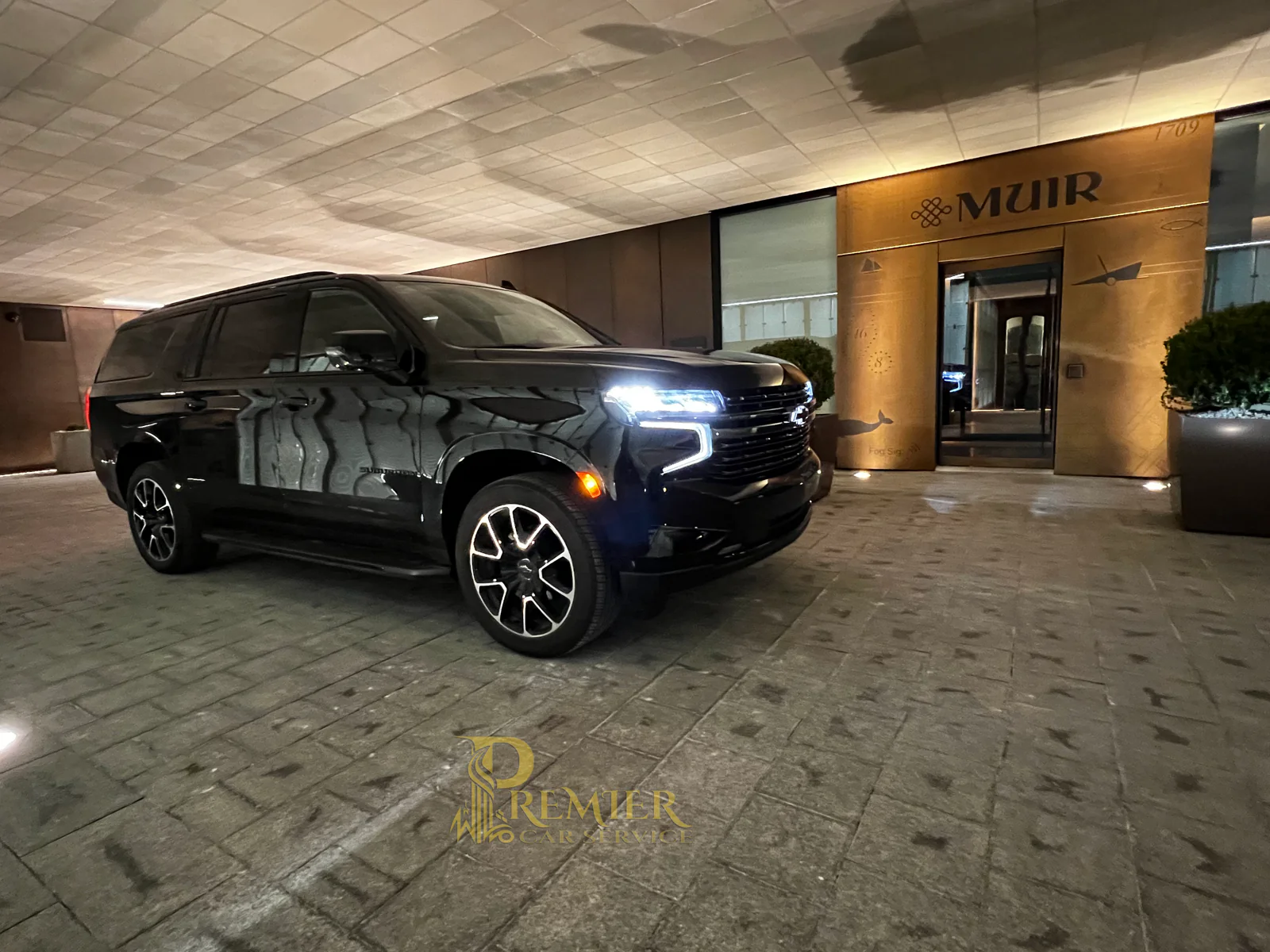 Chevrolet Suburban at the Muir Hotel's covered porte-cochère at dusk